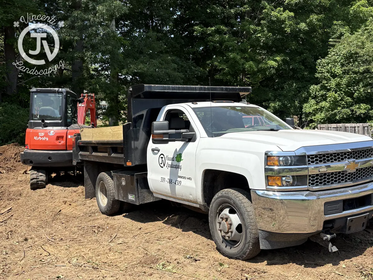 Vincenti Landscaping branded dump truck and excavator on a job site near Plympton, MA