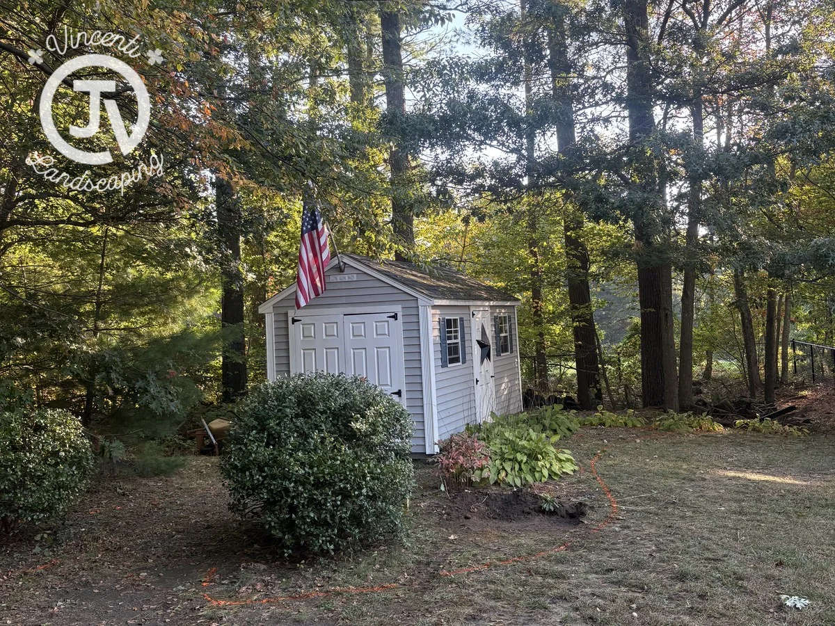 Before: planting beds around a white shed before stone edging and fresh mulch