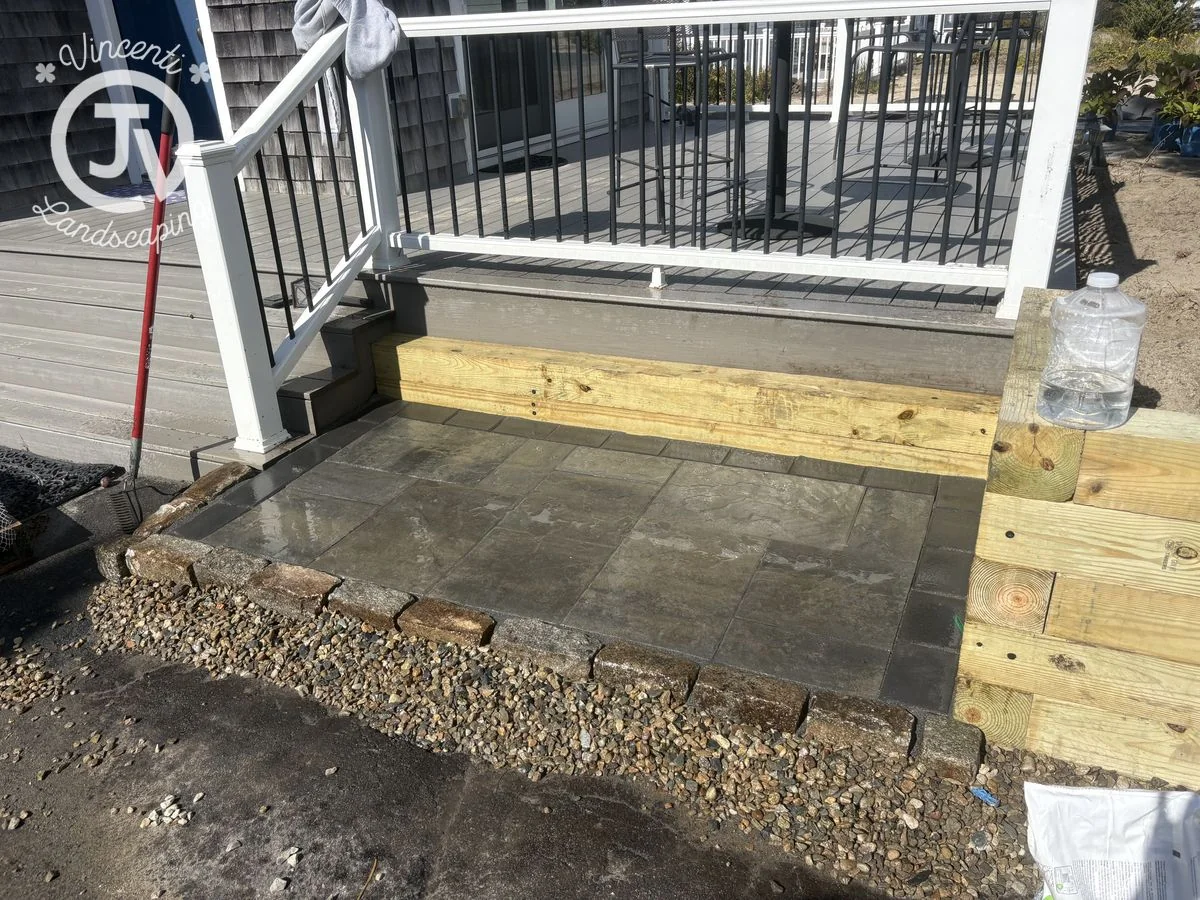 Bluestone landing and timber retaining wall at deck steps installed by Vincenti Landscaping in Marshfield, MA