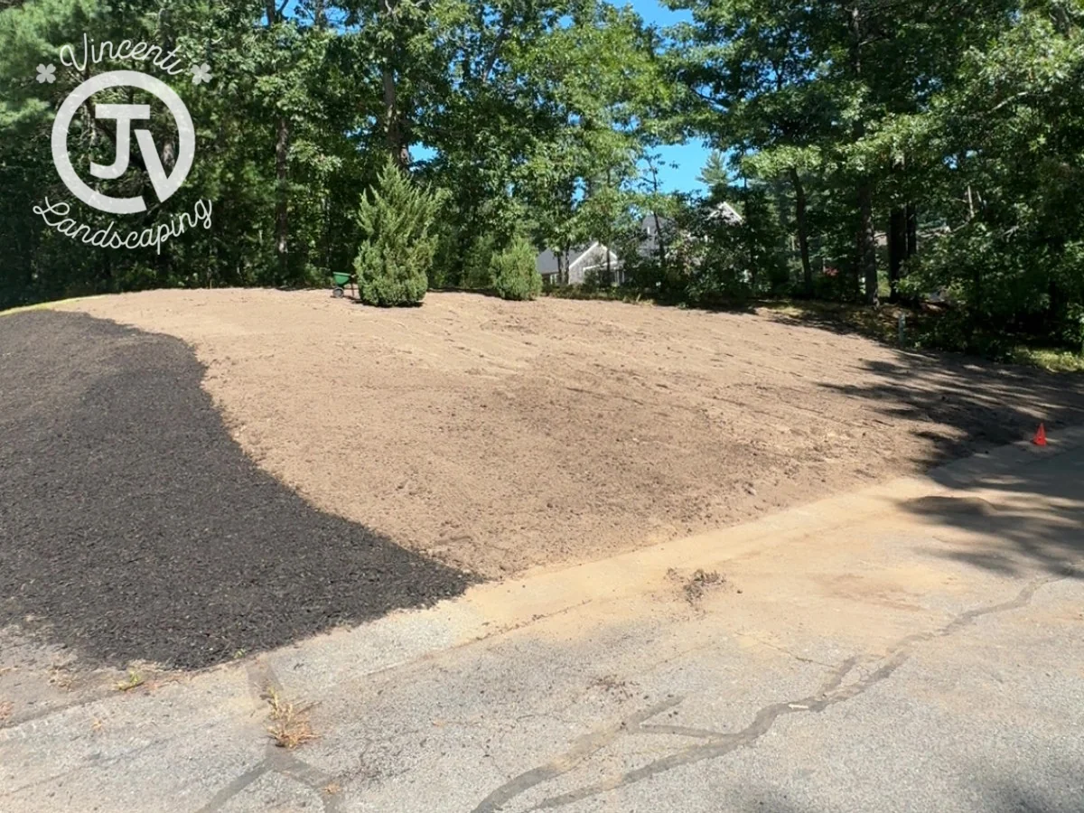Front yard with bare prepared soil beside a driveway before a new lawn is established